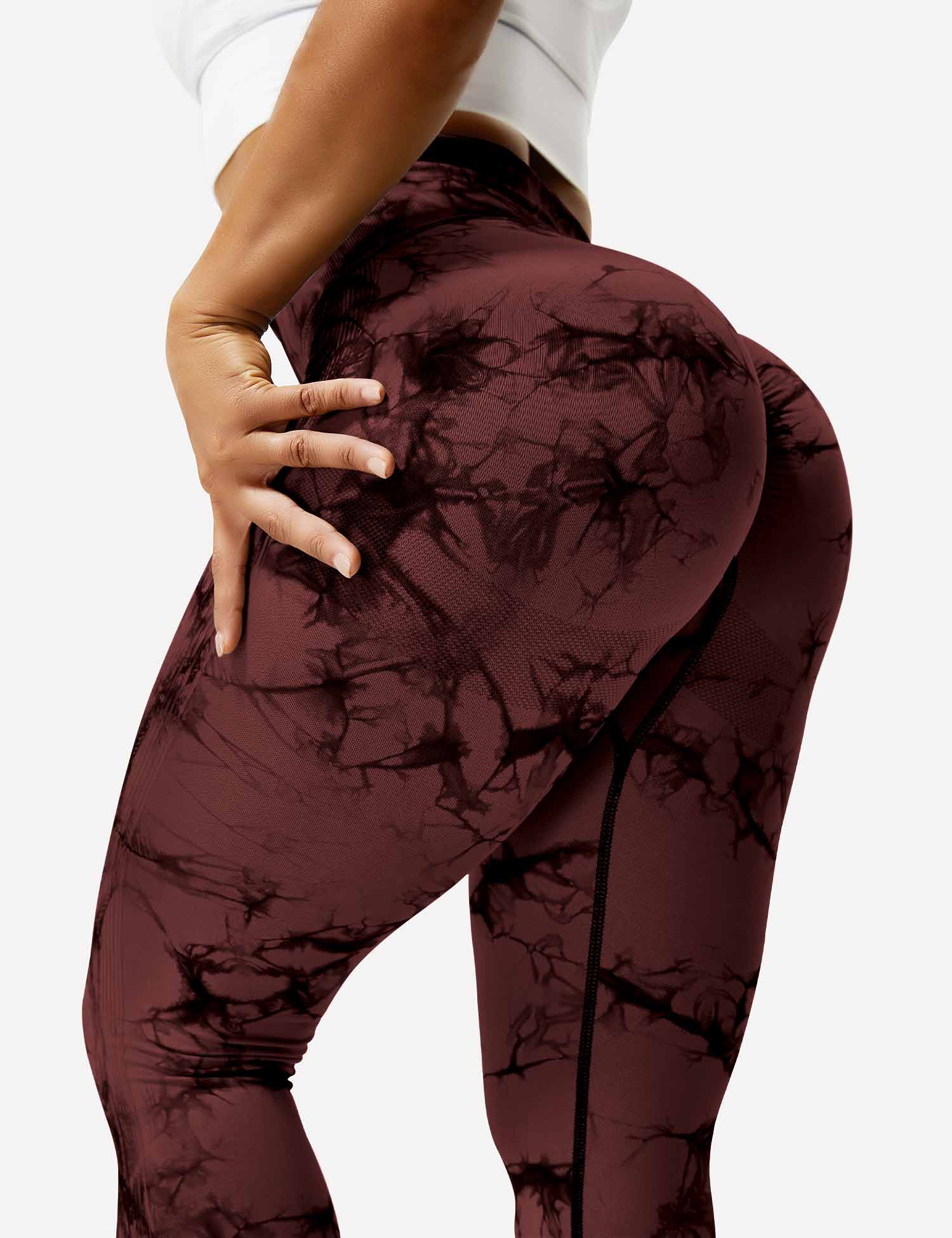 Frau in rotbraunen Leggings mit Marmormuster, Sportbekleidung, figurbetont, elastisch.