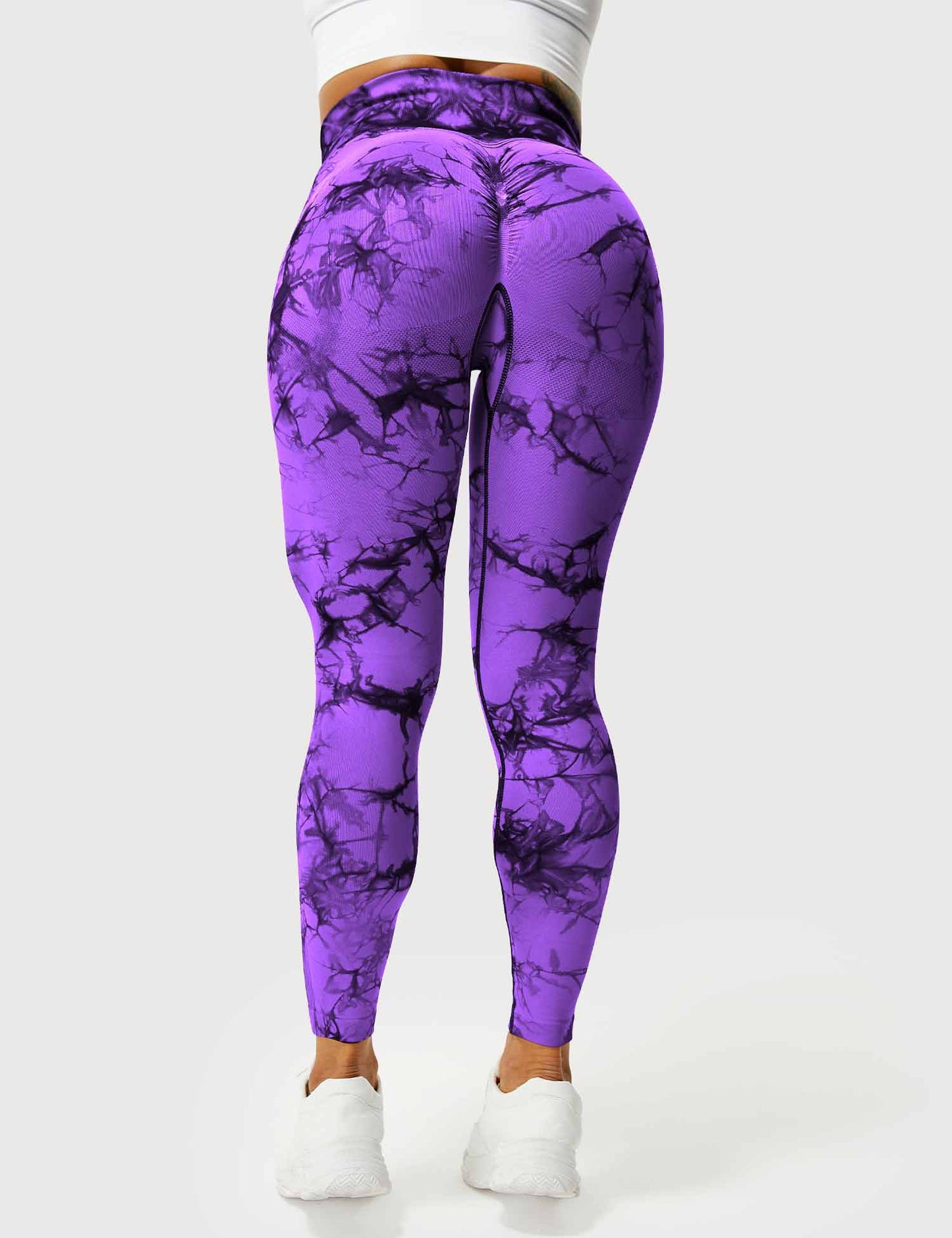 Frau in lila Marmor-Leggings, hoch tailliert, Sportbekleidung, Fitnessmode, Rückansicht.